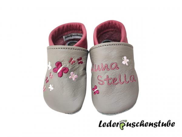 Lederpuschen in steingrau-altrosa; links 2 Schmetterlinge (bordeauxe-rosa-creme) Namen (altrosa) und rechts Stickerei 9 Schmetterlinge (bordeauxe-rosa-altrosa-creme) 
